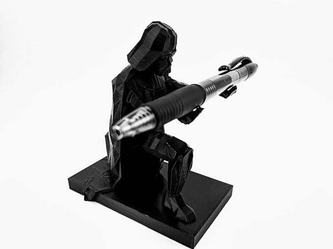 3D printed Darth Vader holding pens like lightsabers on a cluttered desk, bringing dark side vibes to office organization.
